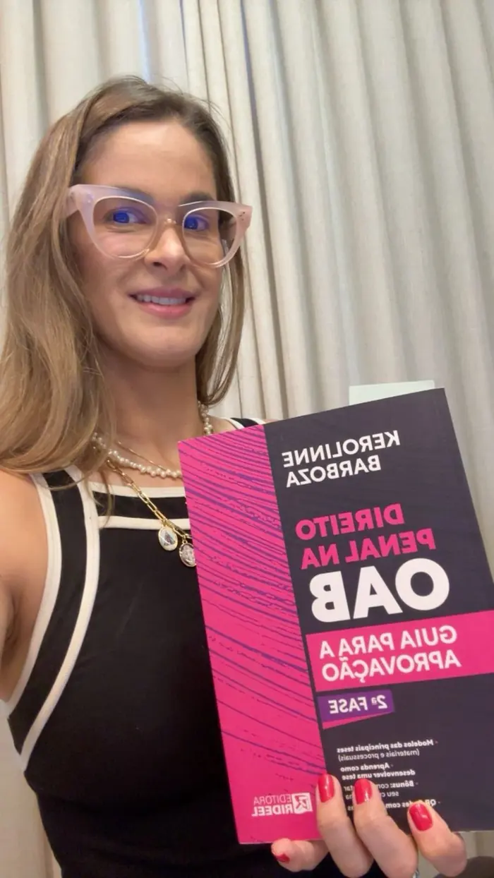 Aluna segurando o livro de Direito Penal para a OAB